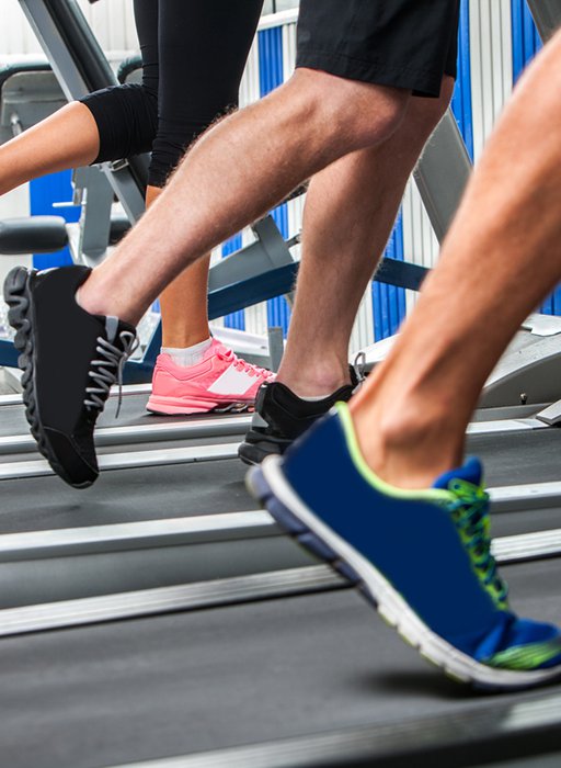 Group of legs wearing sneakers running on treadmill